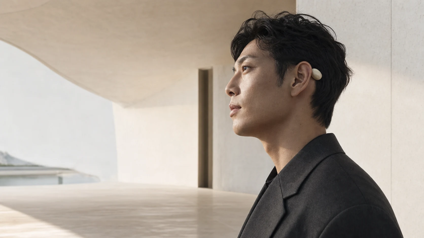 A person wearing a bone-white ThoughtOps stone behind the ear